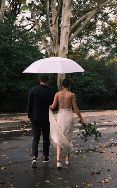 A groom holding an umbrella for his bride